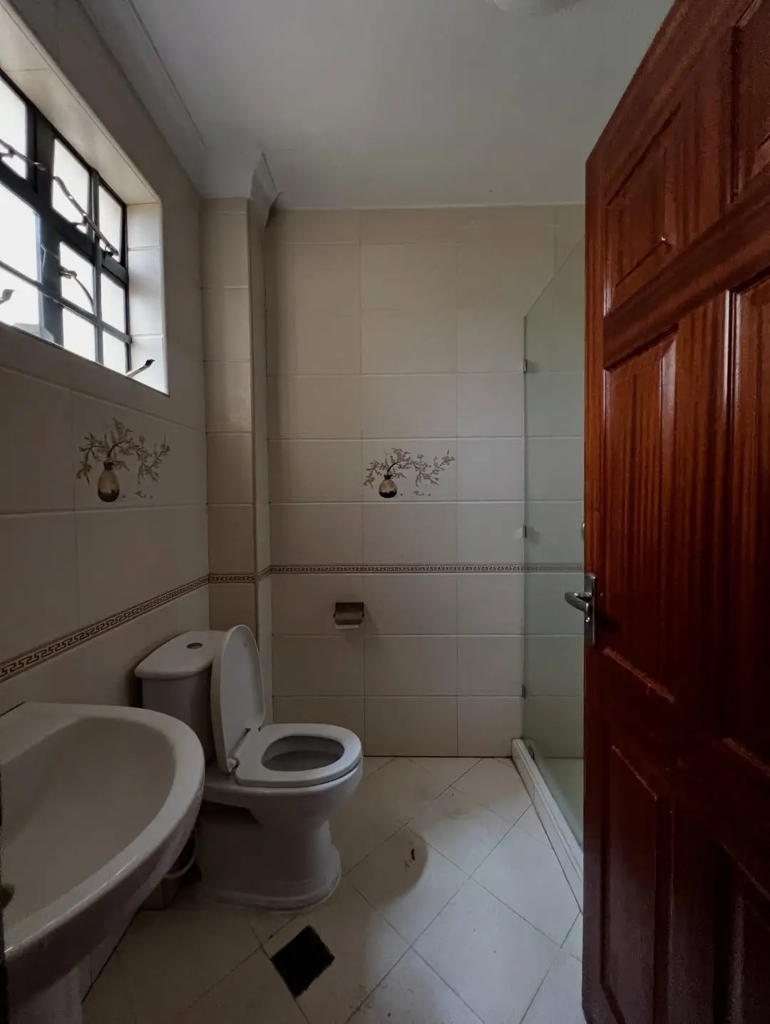 Clean bathroom with toilet, sink, tiled shower enclosure