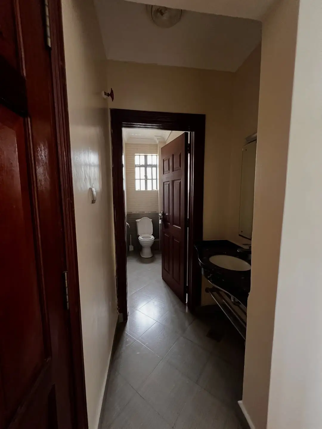 Narrow hallway with dark wooden doors and tiled flooring