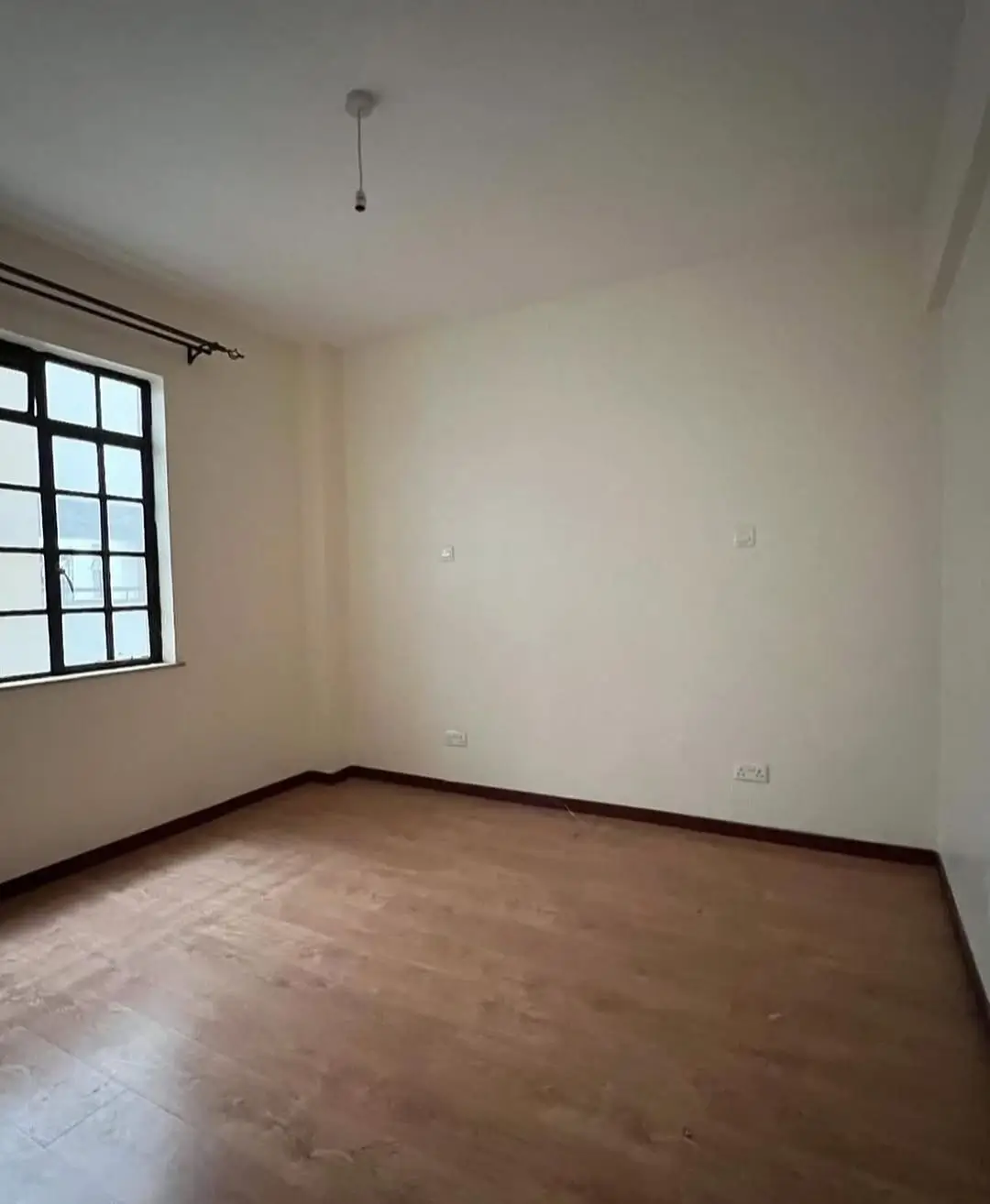 Empty bedroom with wooden flooring and natural light window