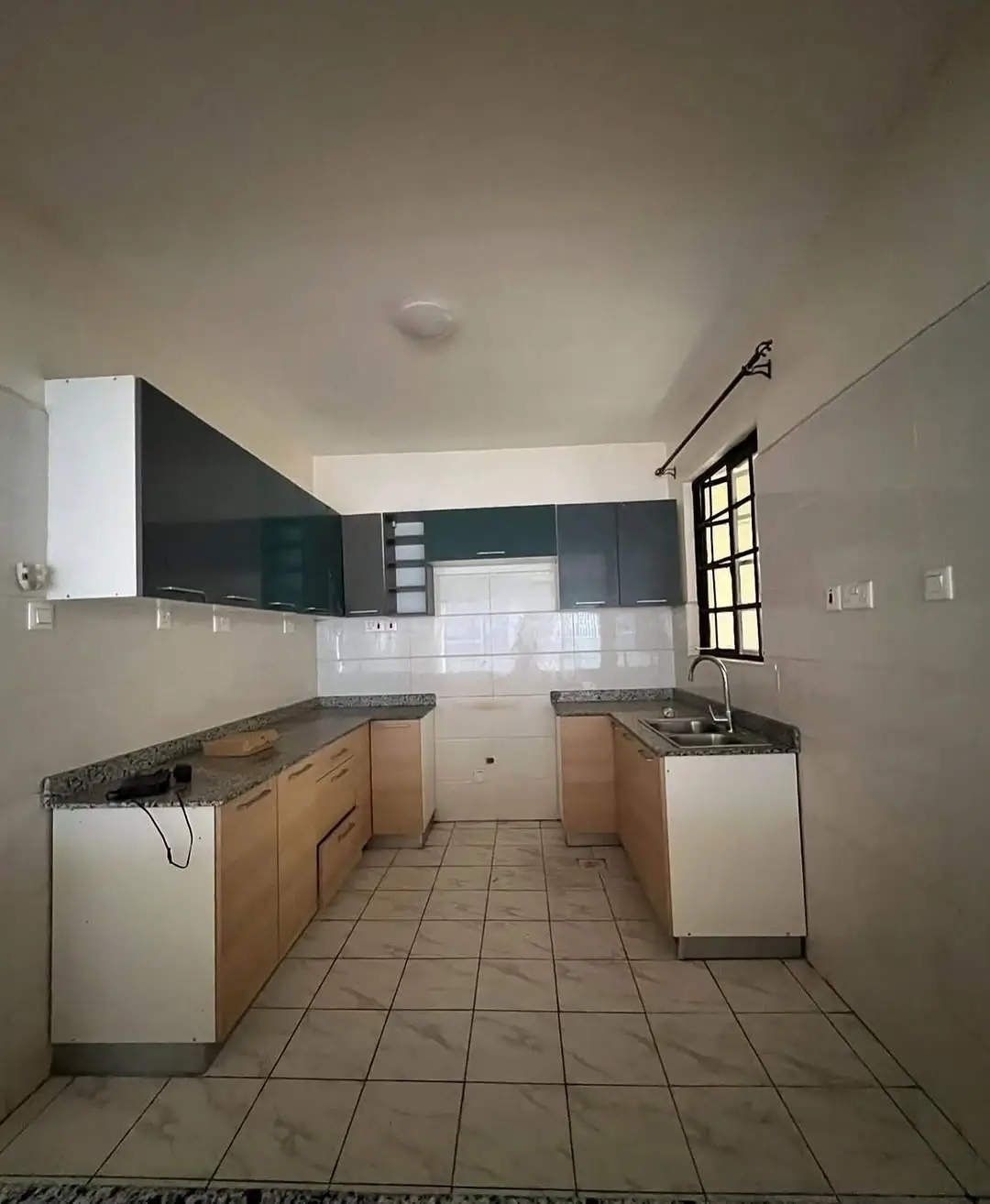Modern U-shaped kitchen with dark cabinetry and tile flooring