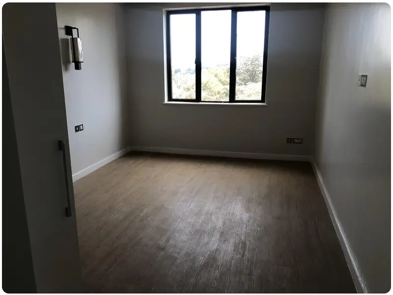 Spacious bedroom with large window, wooden flooring, neutral decor