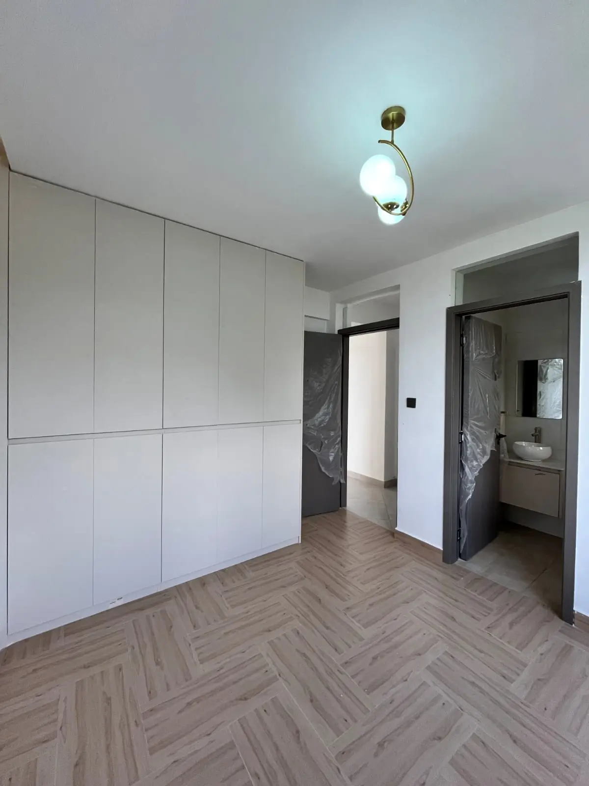 Spacious bedroom with built-in white wardrobes and herringbone flooring