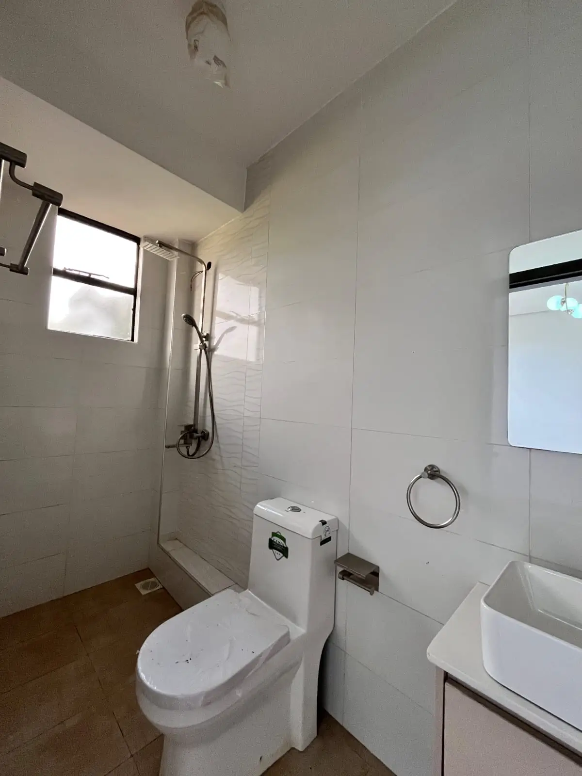 Compact bathroom with toilet, sink, and shower enclosure