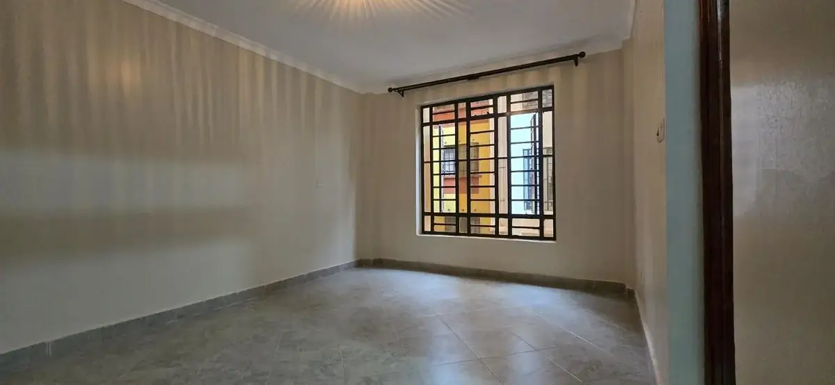 Unfurnished bedroom with barred window and neutral walls