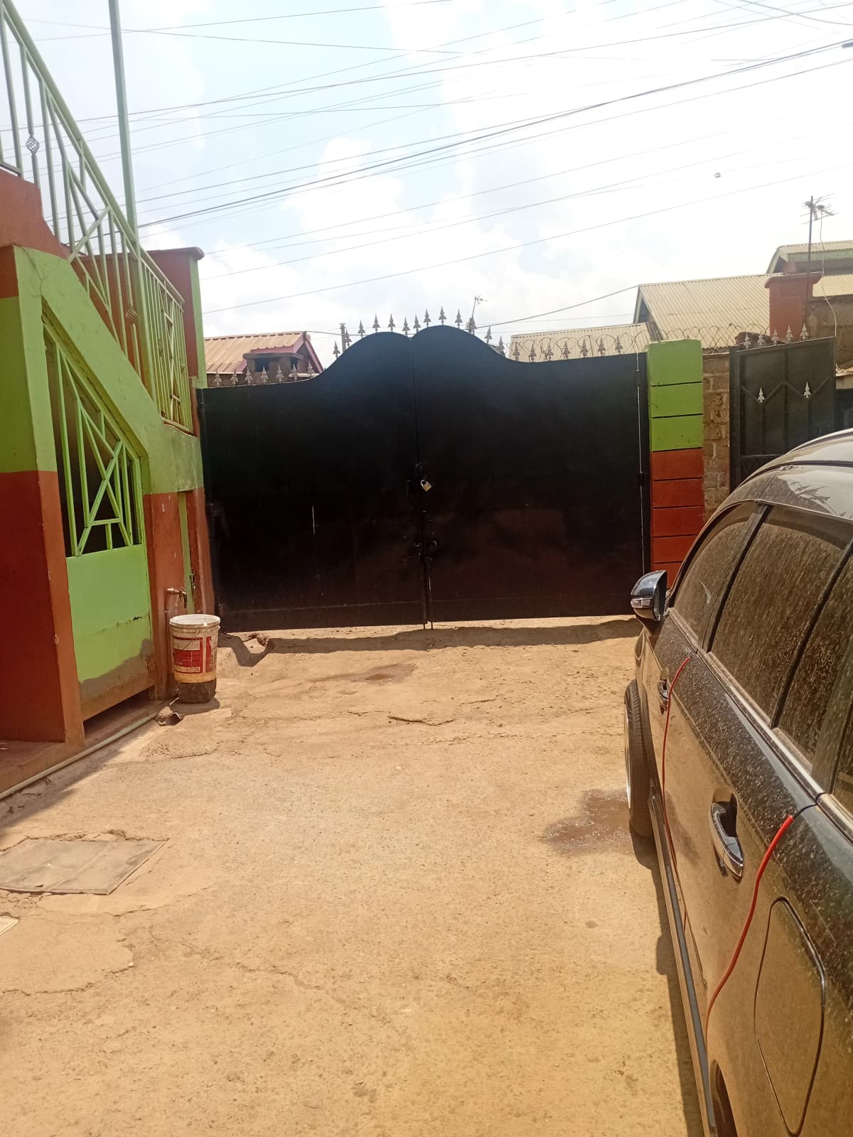 Compound driveway with black metal gate and parked vehicle