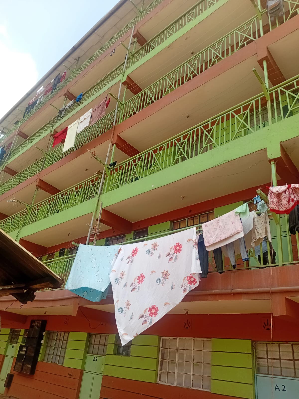 Multi-story residential building facade with green railings and balconies