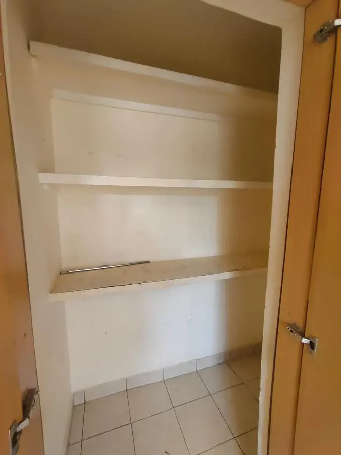 Empty pantry with built-in shelving and tile flooring