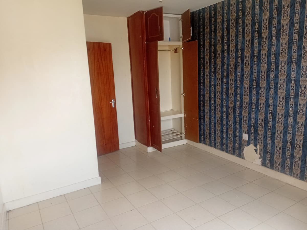 Empty bedroom with tiled floor and wooden wardrobes