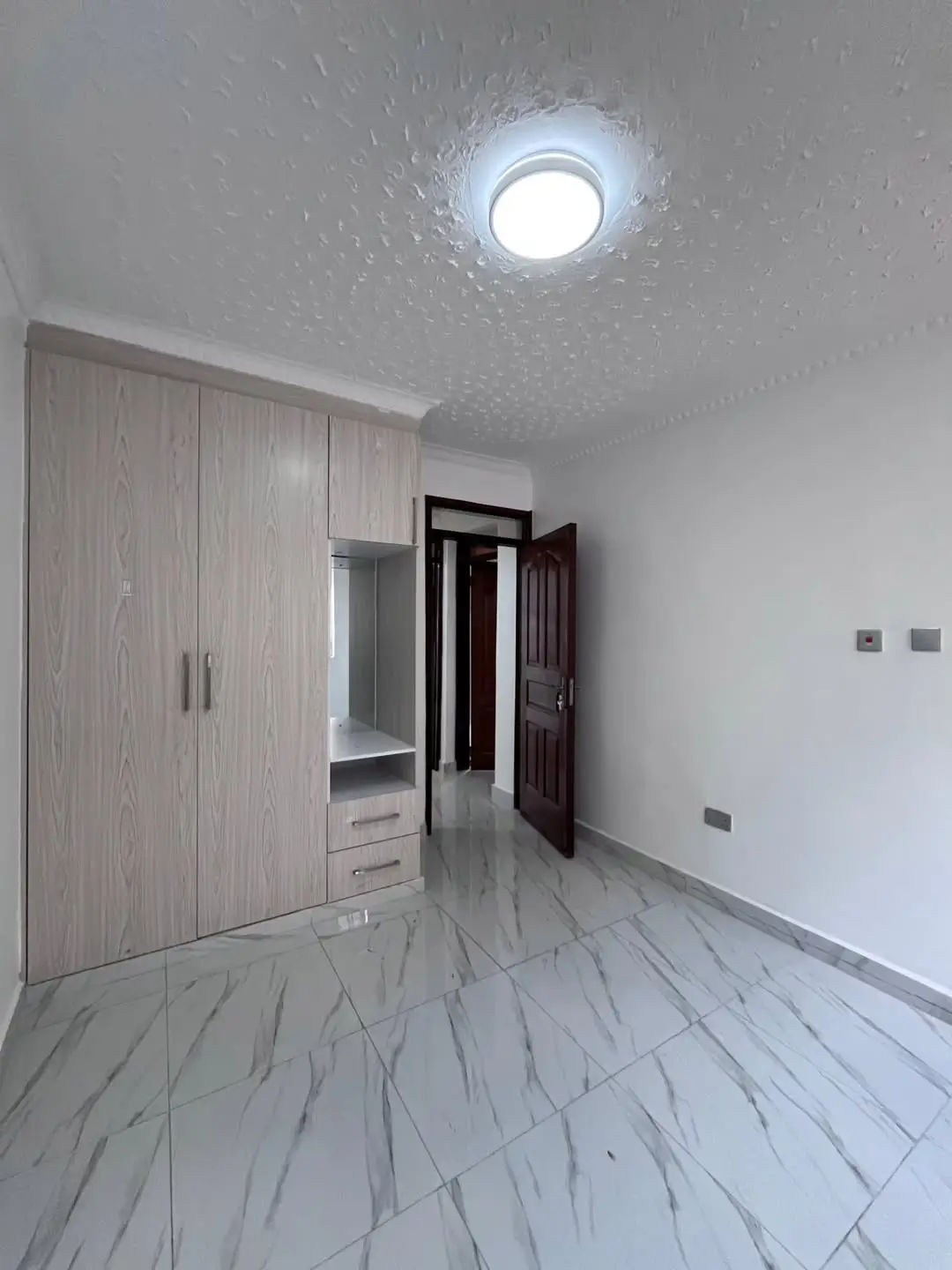 Empty bedroom with built-in wardrobe and marble flooring