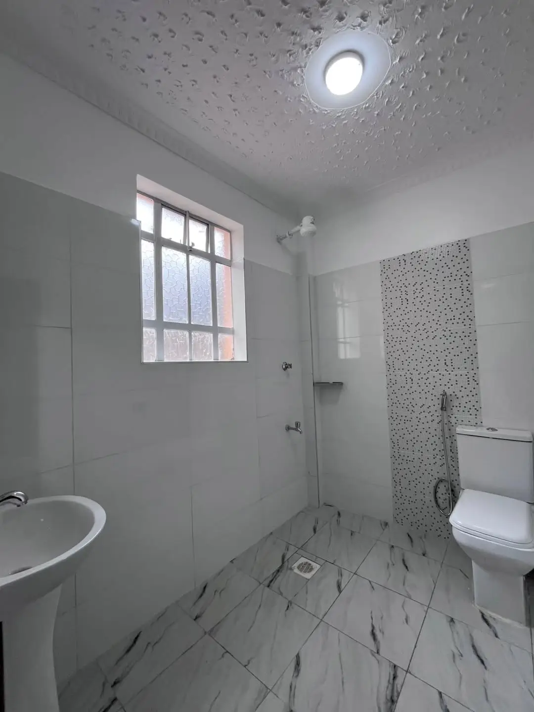 Modern bathroom with marble-effect flooring and shower area
