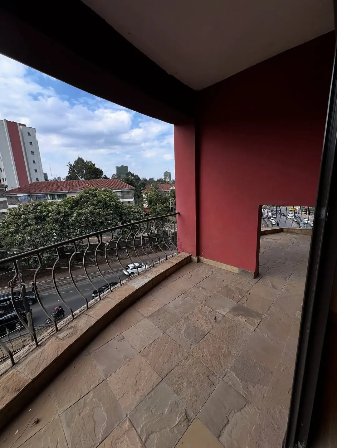 Red-walled balcony with railing overlooking urban landscape