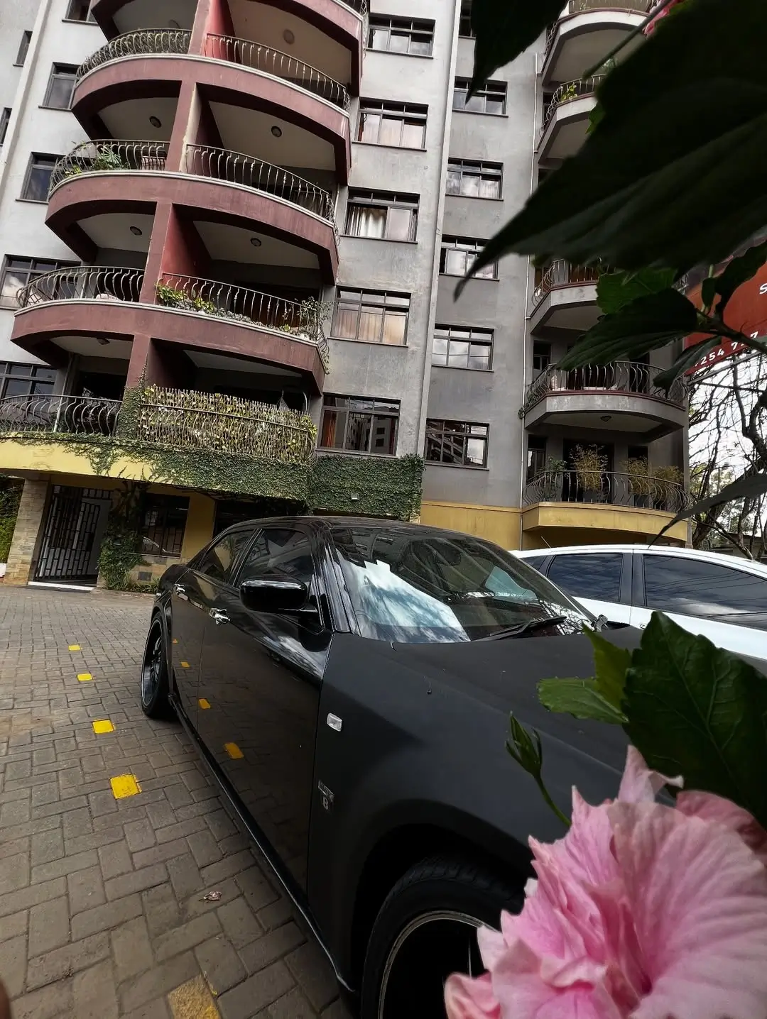 Covered parking bay with multi-story residential building facade