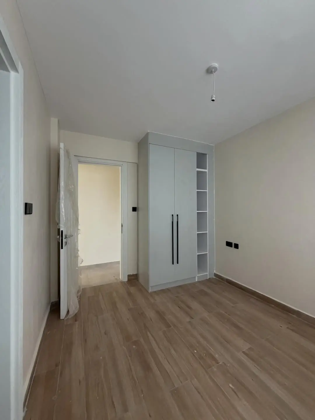 Empty bedroom with built-in wardrobes and wooden flooring
