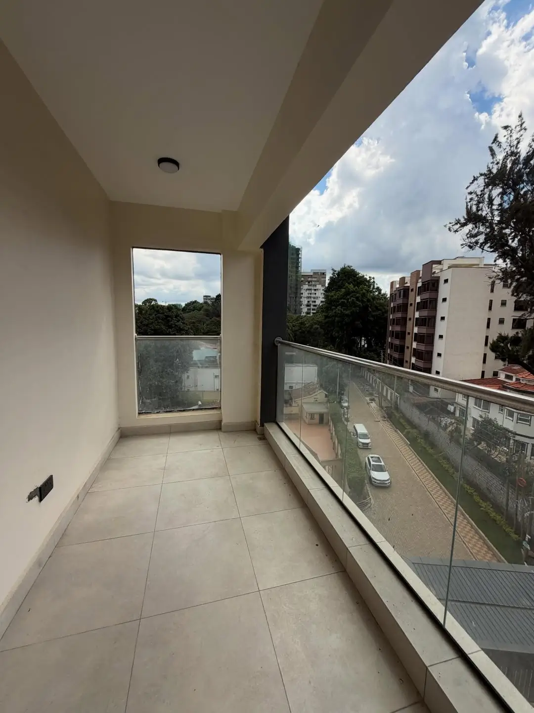 Spacious balcony with glass railing overlooking urban street