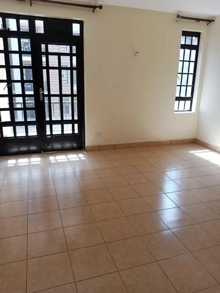 Empty living room with terracotta tile floor and large windows