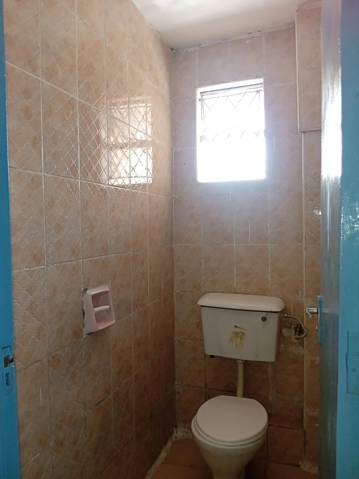 Compact bathroom with toilet, cistern, and tiled walls