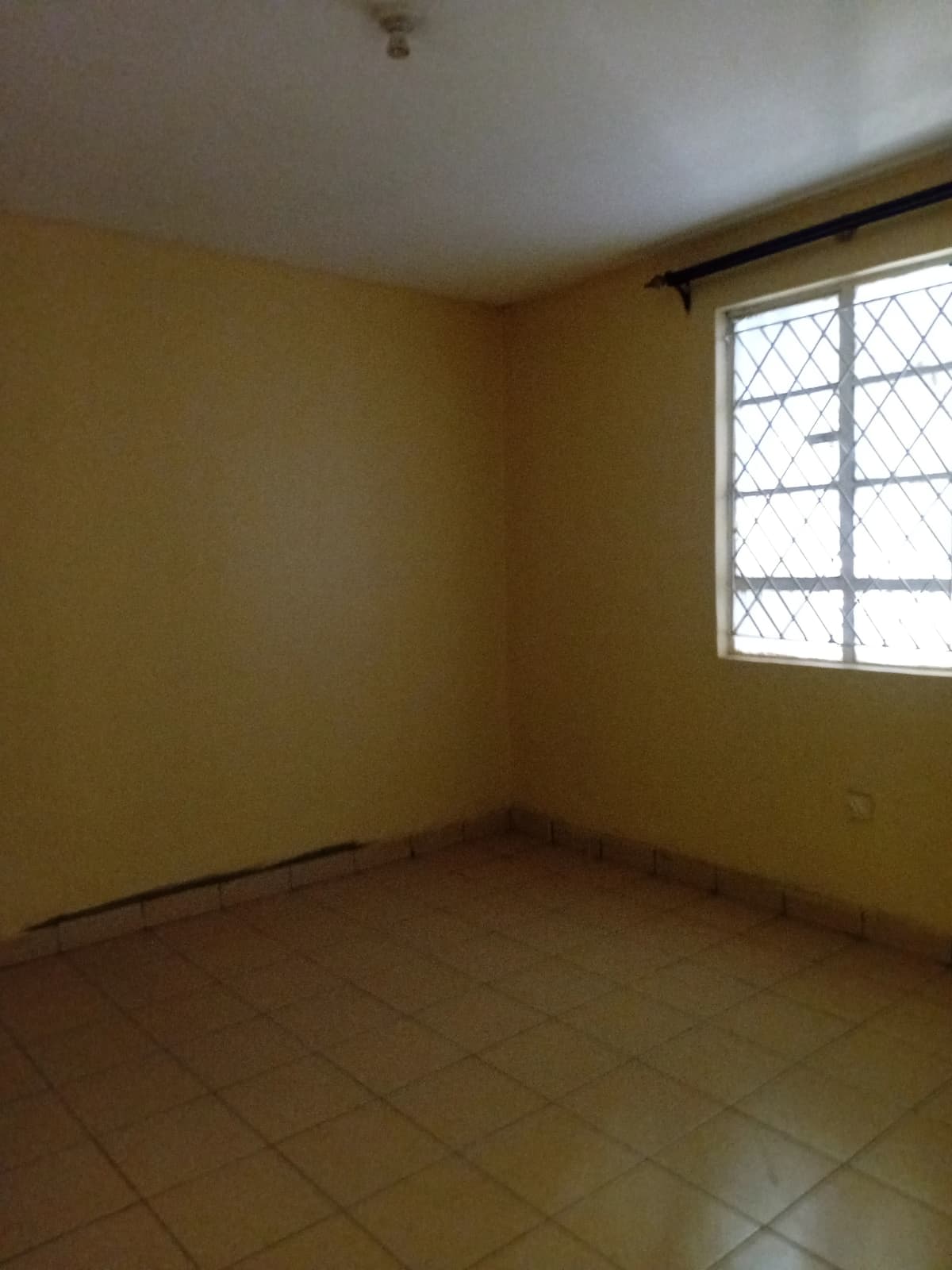 Empty bedroom with yellow walls and barred window