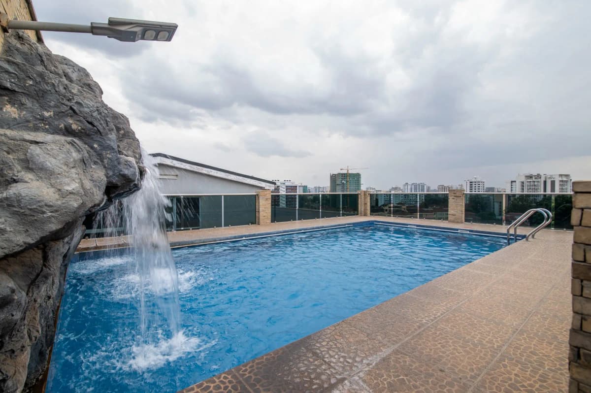 Rooftop swimming pool with waterfall feature and city views
