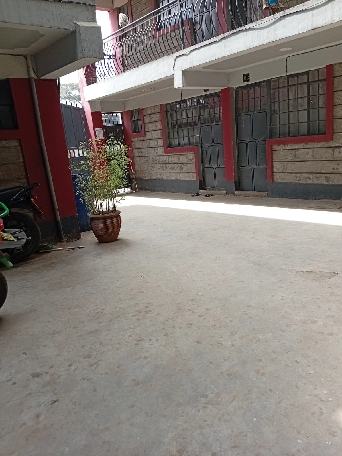 Ground floor compound entrance with red-trimmed doors and potted plant