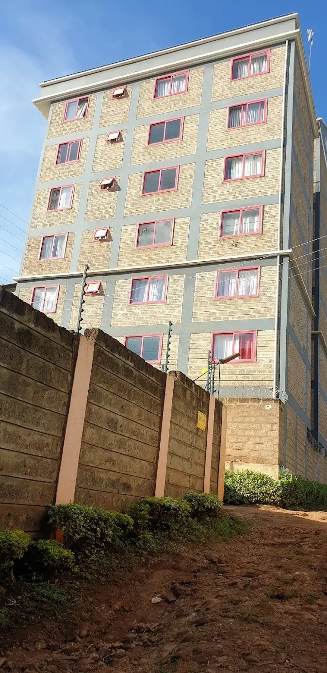 Multi-story residential building with stone facade and surrounding walls