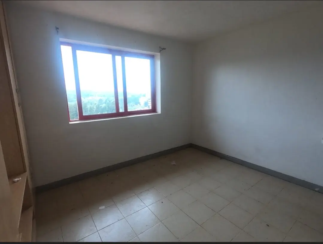 Bright empty bedroom with large window and tiled flooring