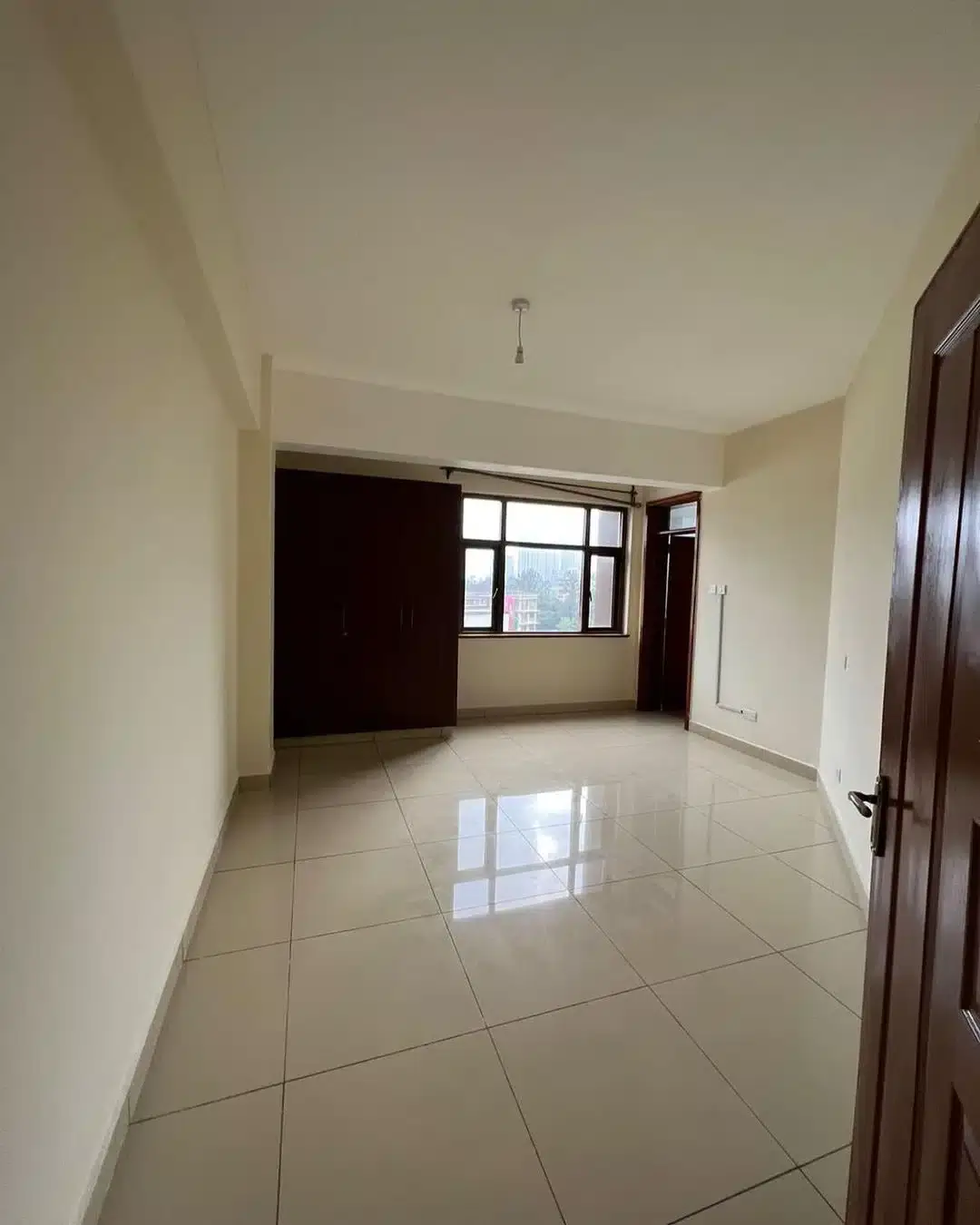 Spacious empty living room with polished tile flooring and natural light