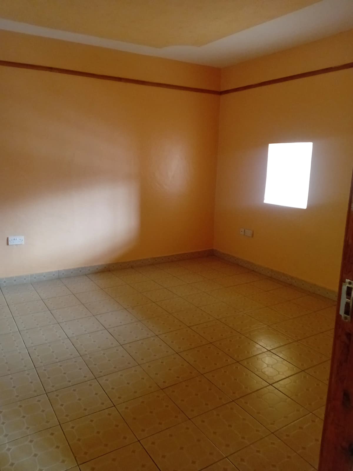 Empty bedroom with terracotta tiles and high window