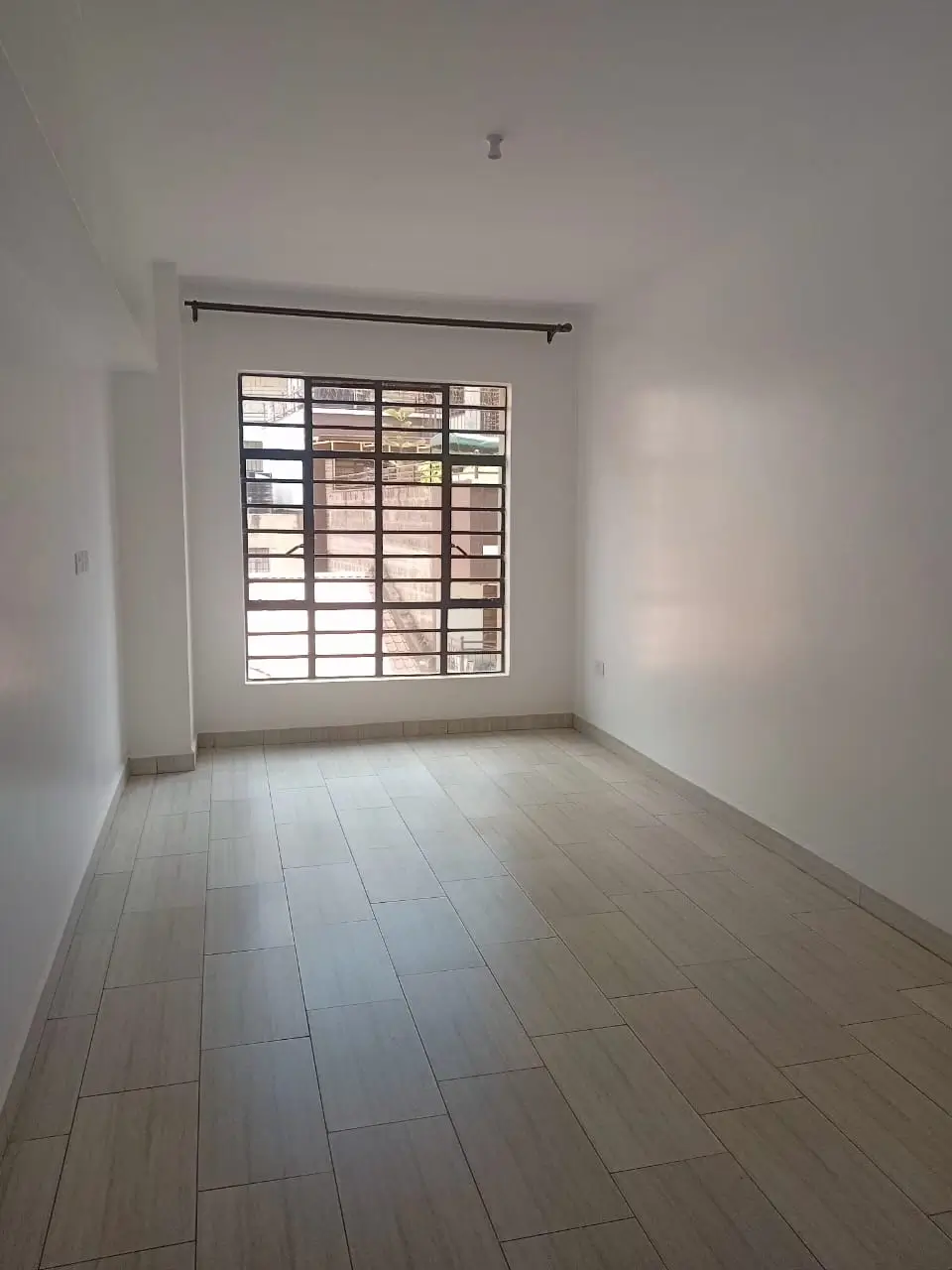 Minimal bedroom with tiled flooring and barred window