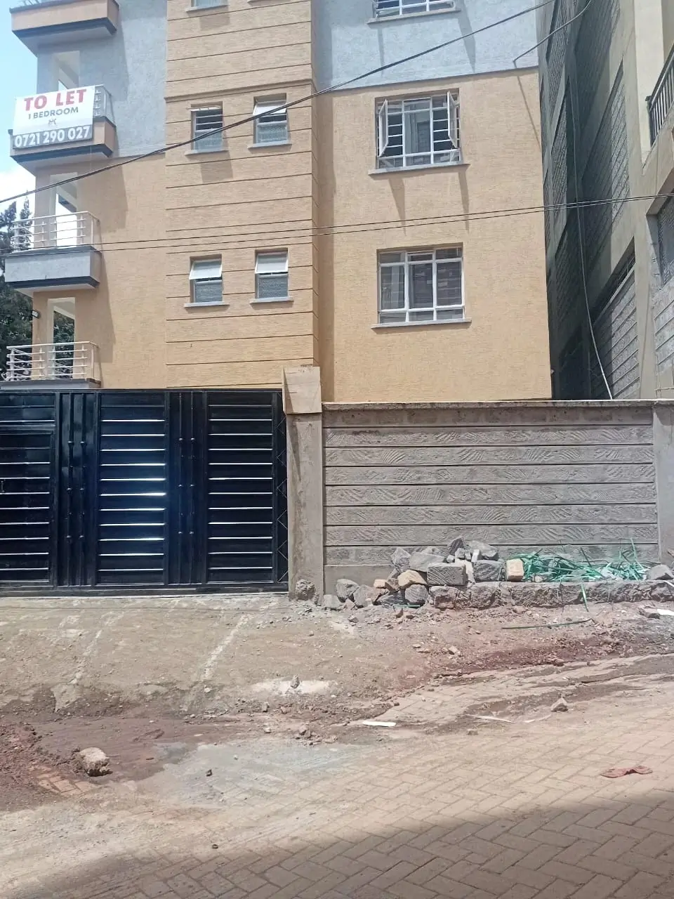 Multi-story residential building with metal gate and compound entrance