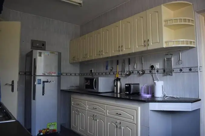 Compact kitchen with cream cabinets, black countertop, appliances