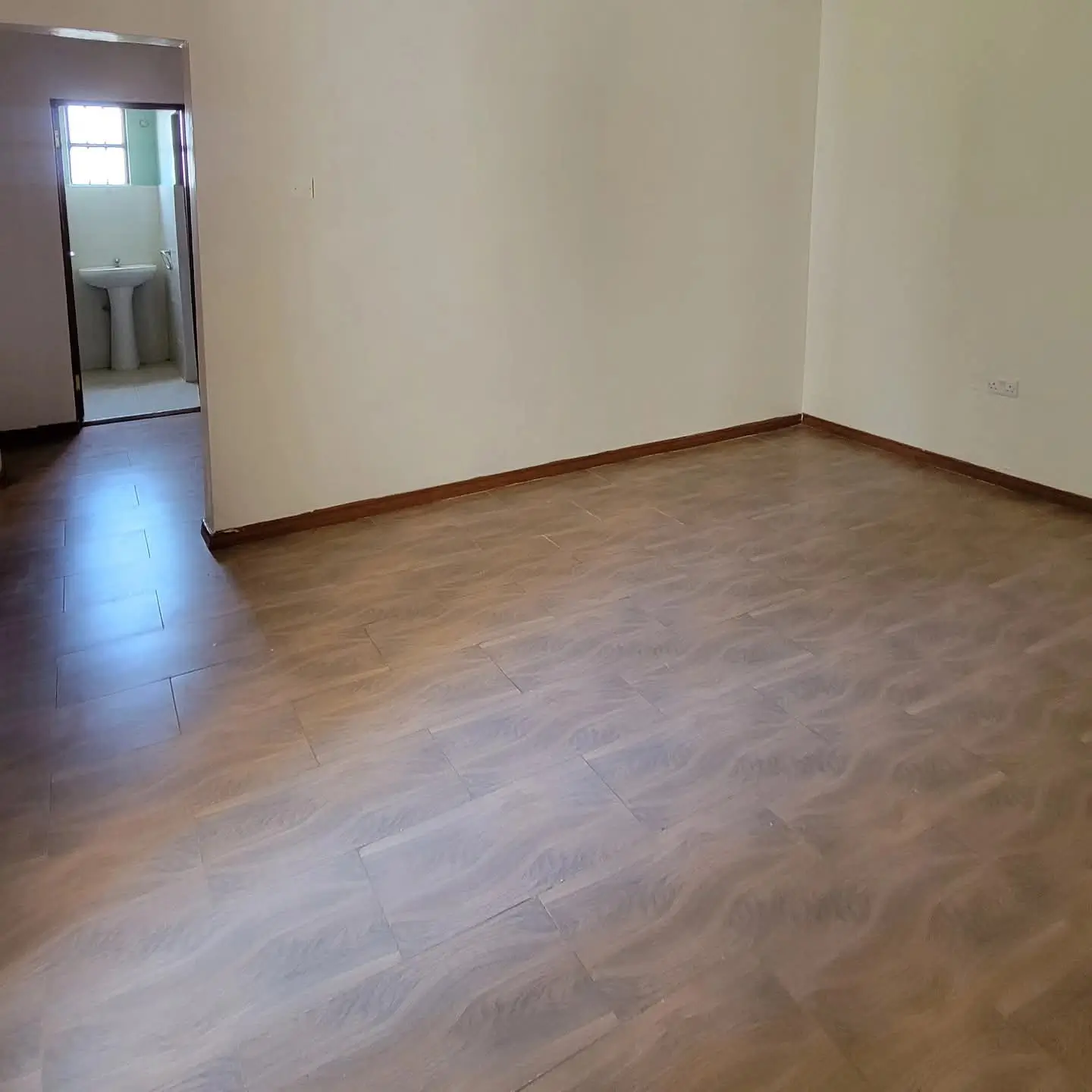 Empty bedroom with wooden floor and en-suite bathroom access