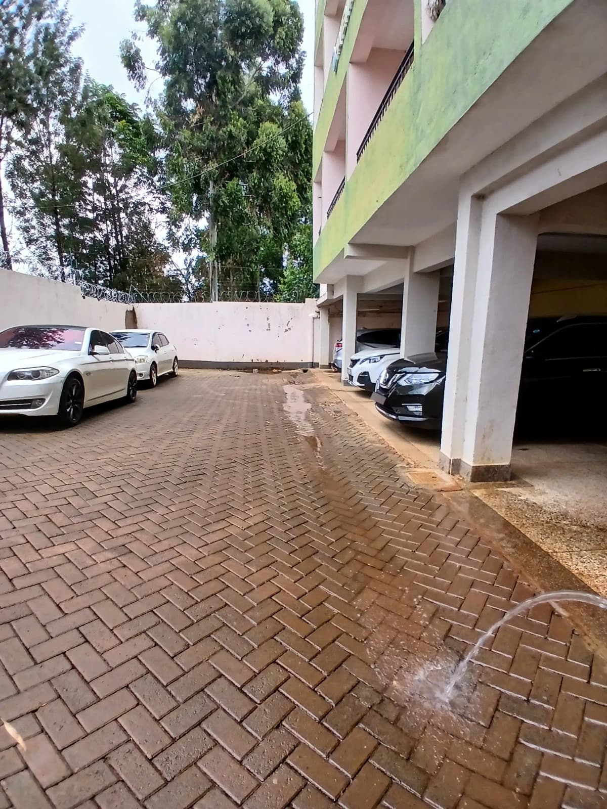 Covered parking garage with multiple vehicles and brick driveway