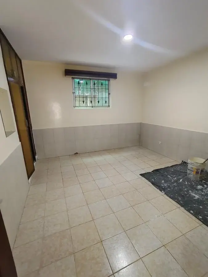 Bare bedroom with tiled floor and barred window