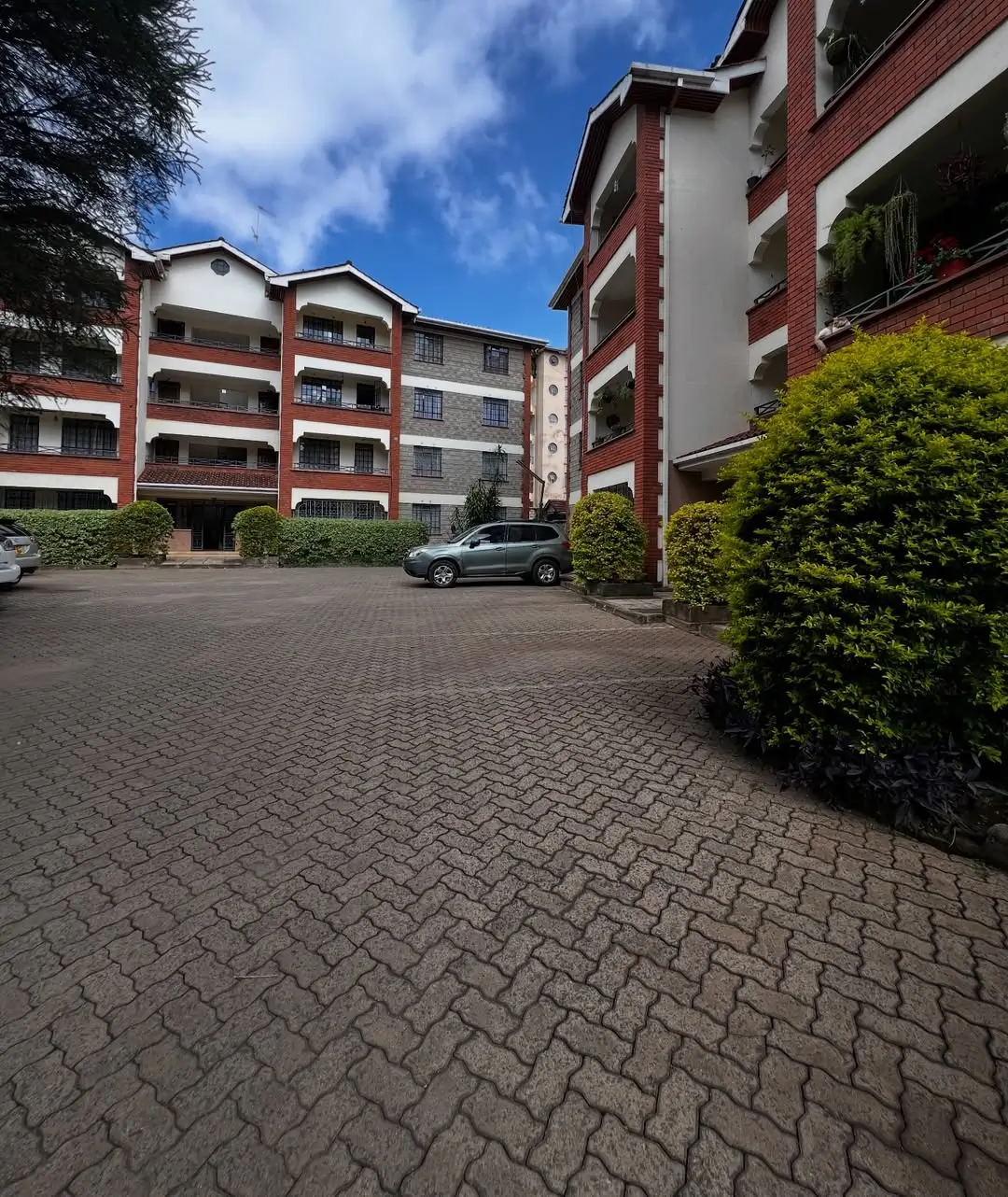 Multi-story residential complex with paved compound and parked car