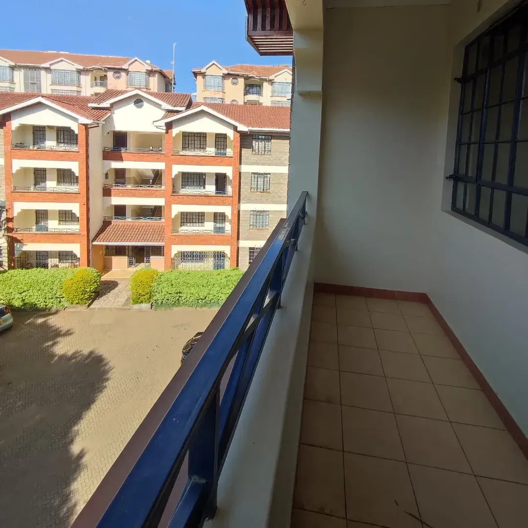 Spacious balcony with blue railing overlooking residential compound