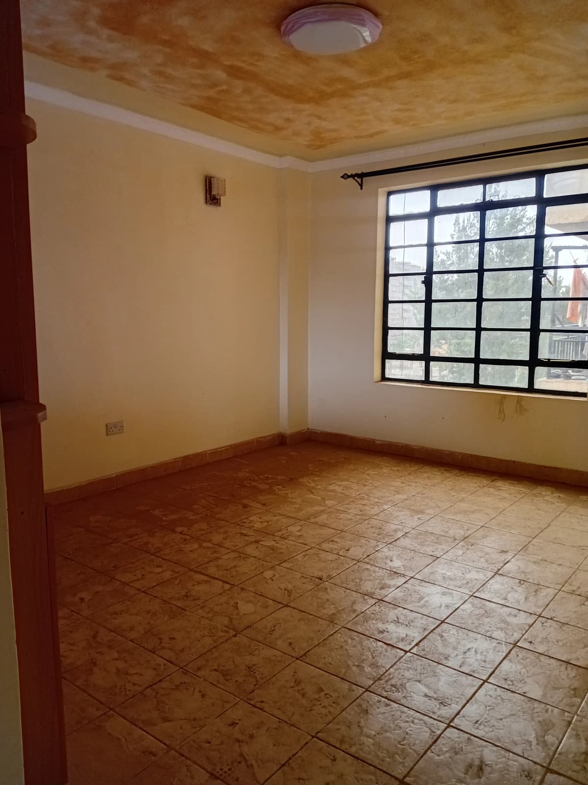 Spacious bedroom with terracotta tiles and large window