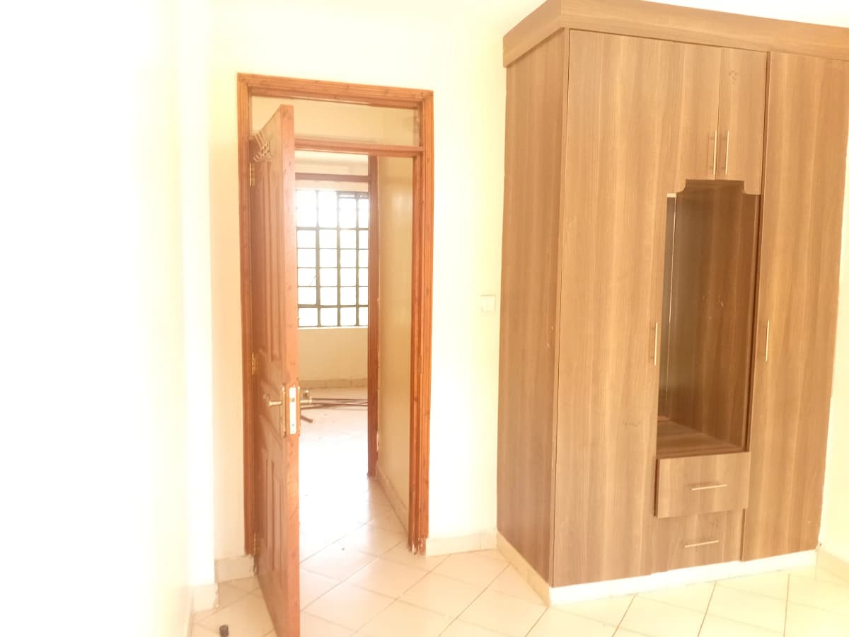 Spacious bedroom with wooden wardrobe and open door view
