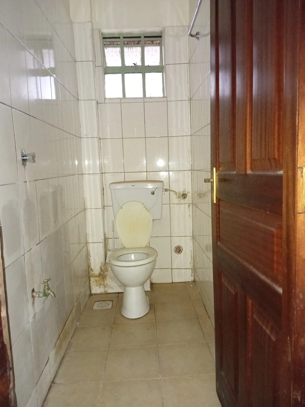 Compact bathroom with toilet, white tiles, natural light window