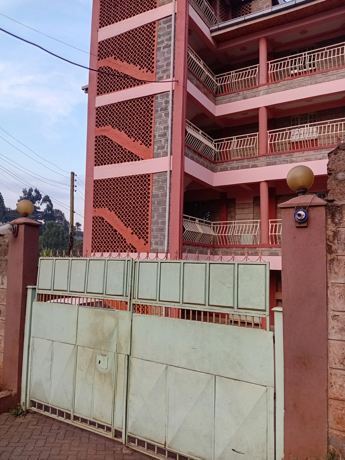 Red-brick residential building with metal gate entrance