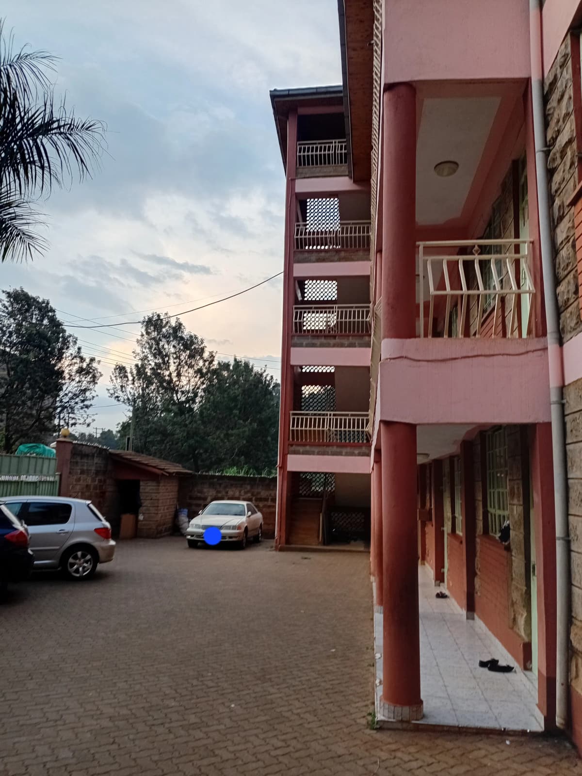 Red multi-story residential building with ground-level parking area