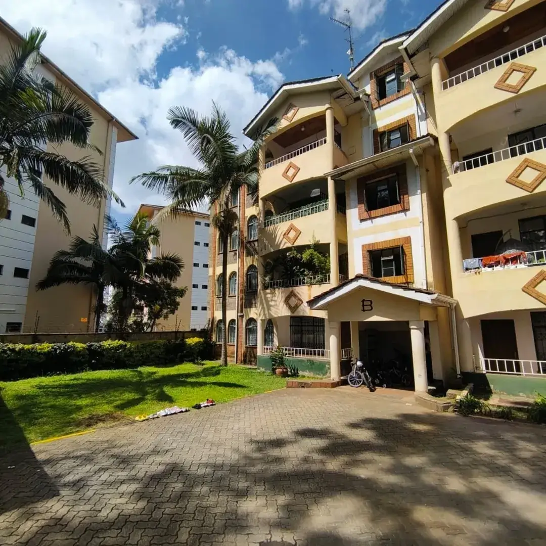 Multi-story residential building with manicured grounds and palm trees
