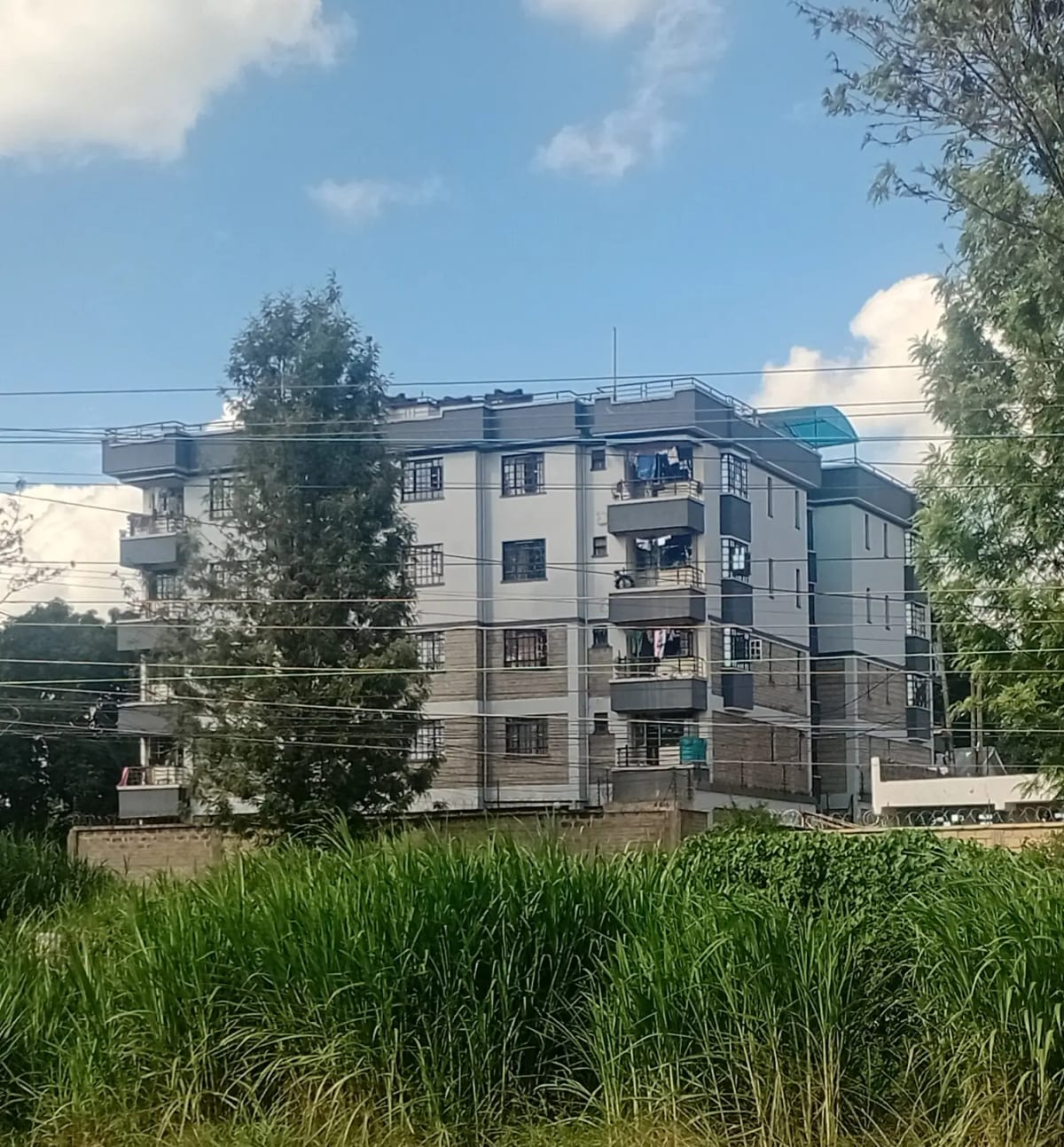 Multi-story residential apartment building with green compound grounds