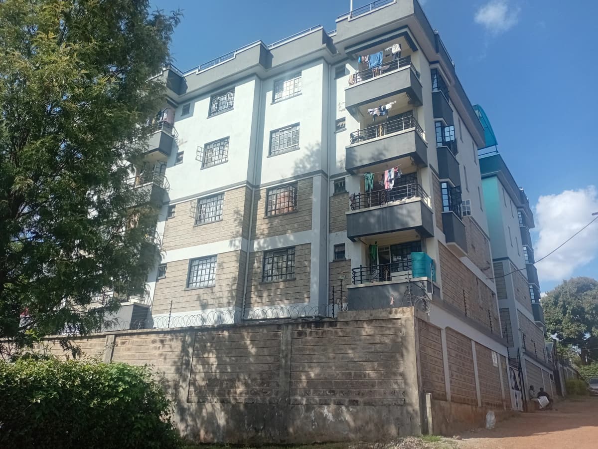 Multi-story residential apartment building with balconies and brick perimeter wall
