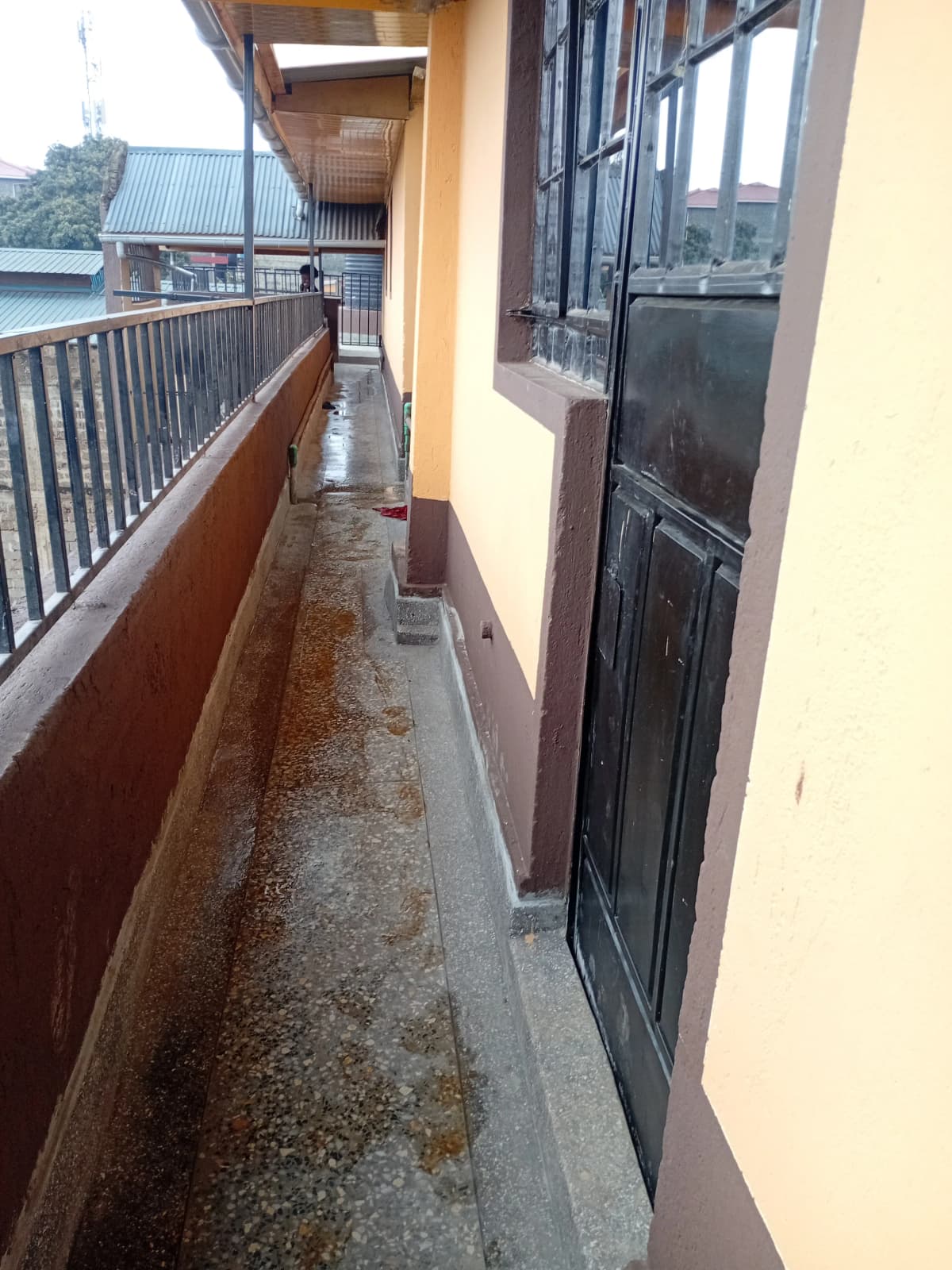 Narrow outdoor balcony with metal railing and concrete flooring