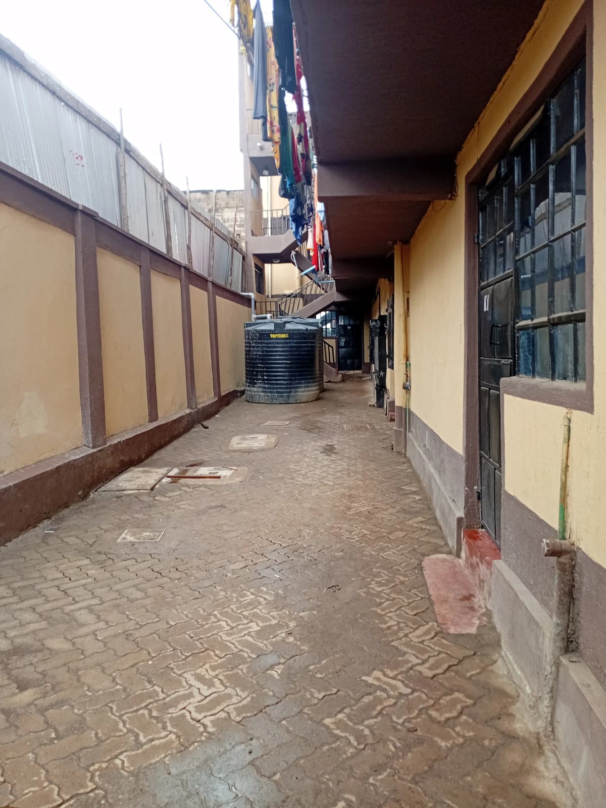 Narrow compound driveway with paved ground and perimeter walls