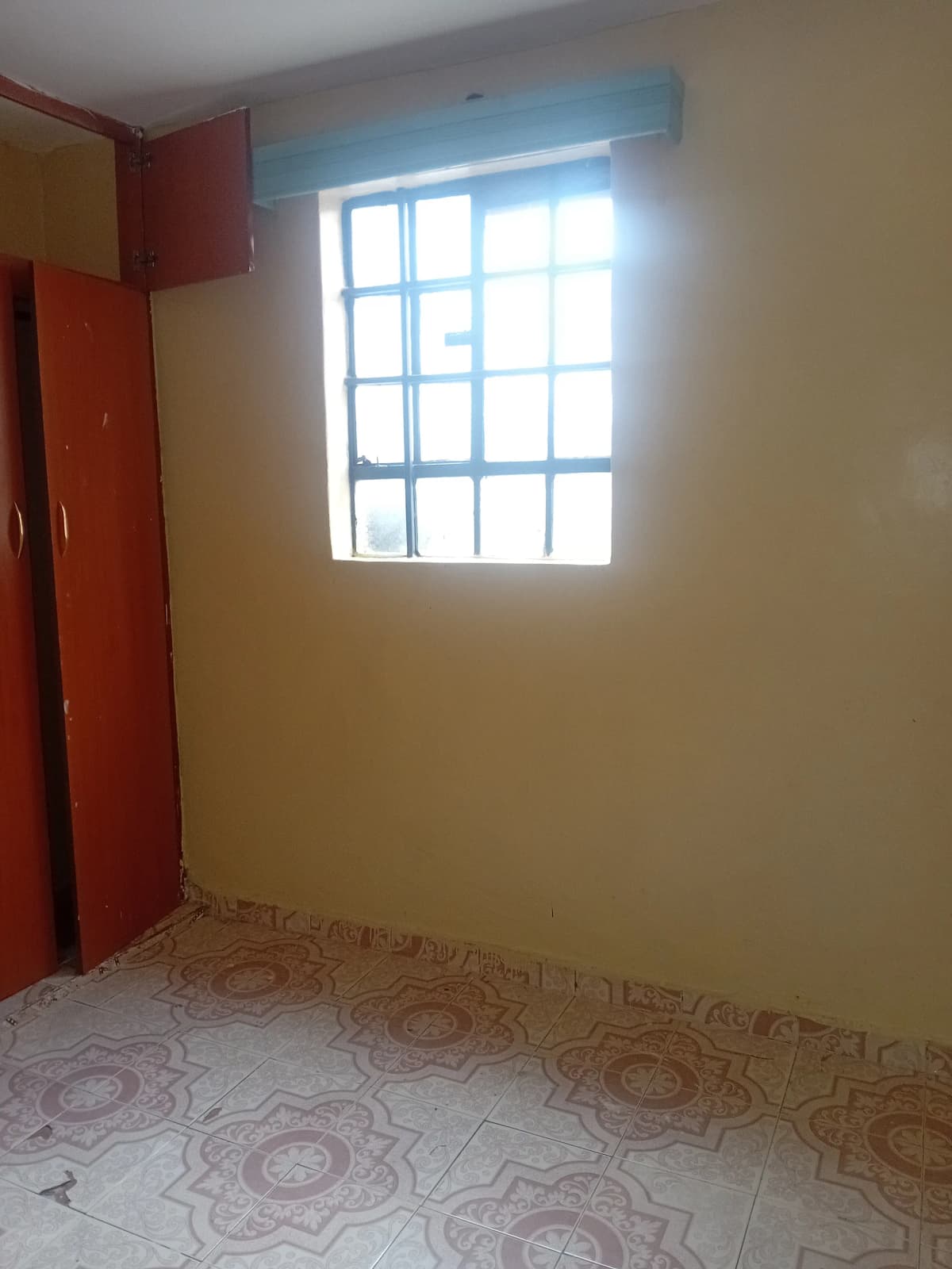 Compact bedroom with patterned floor tiles and bright window