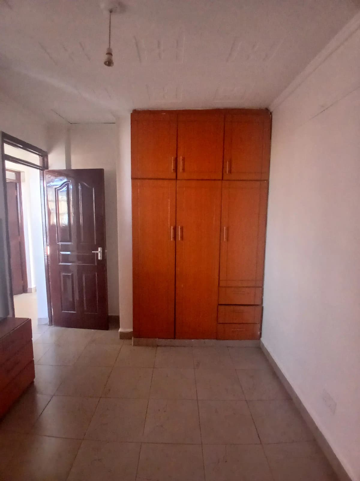 Bedroom with large red wooden wardrobe and tiled flooring