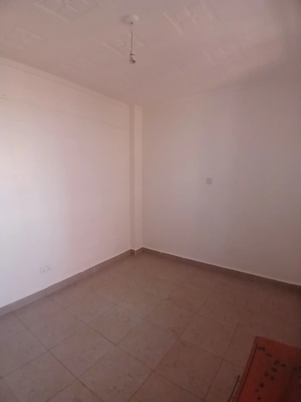 Empty bedroom with brown tile flooring and white walls