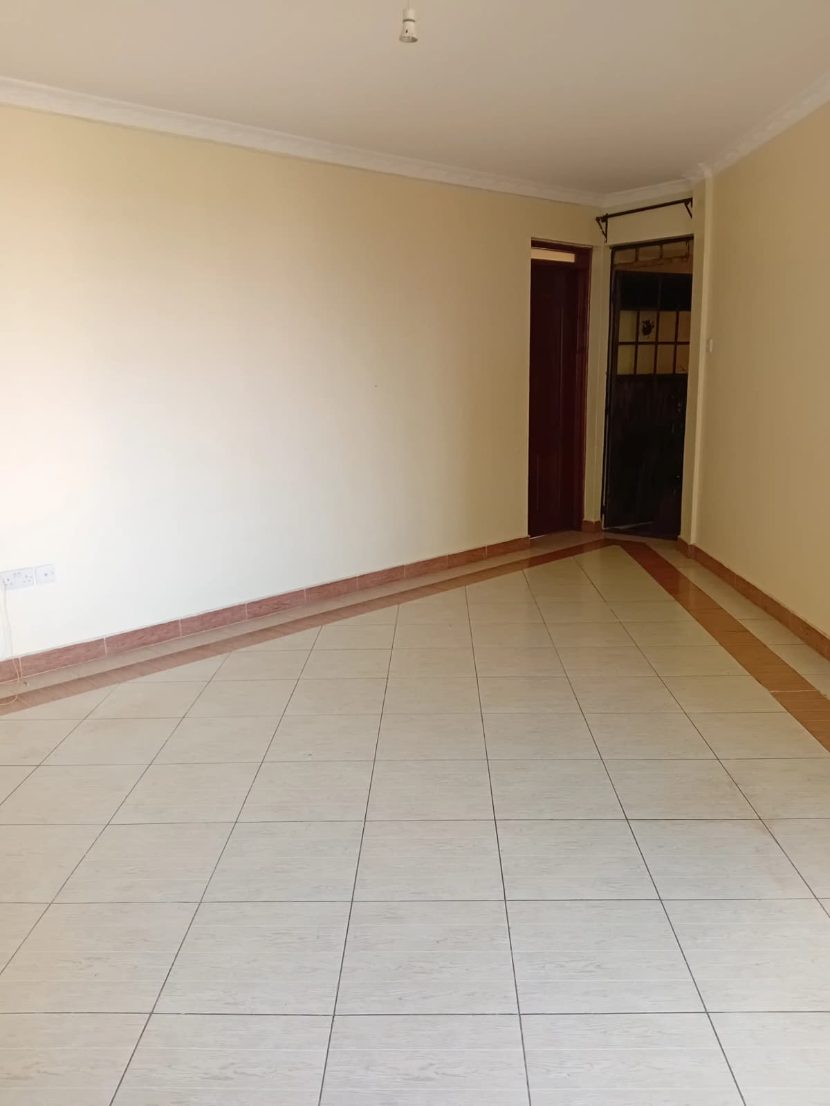 Empty living room with tile flooring and cream walls