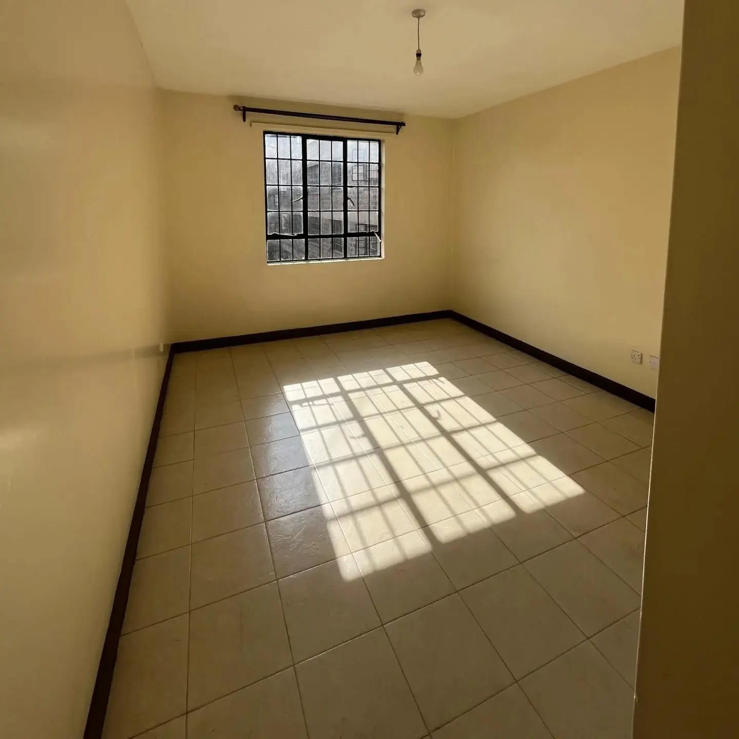 Bright empty bedroom with tiled floor and barred window